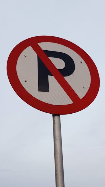 Four blue parking permit signs mounted on slim metal posts in front of a modern exterior wall composed of vertical silver metal panels. The signs display a prominent white 'P' for parking, with additi